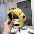 Baroque style yellow knotted headband featuring a large emerald gemstone and sparkling crystals - Yellow