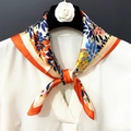 Eleganter Seidenschal mit Blumenmuster an weißem Hemd gebunden zeigt feine Textur und Farben - Orange