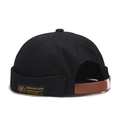 Black canvas docker hat with brown leather strap and decorative yellow text label - Adjustable / Black