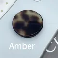 Close-up of a round tortoise shell phone socket with amber patterns on a mobile back - Expanding Stand / Amber