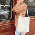 Sac fourre-tout minimaliste en coton et lin blanc porté par un mannequin dans la rue - Beige