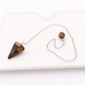 Dettaglio del pendolo in occhio di tigre con catena d'argento su vassoio bianco - Pietra Conica + Catena Argentata / Occhio di tigre