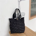 Close-up of black and white polka dot tote bag with metal snap button and pleated fabric - Black