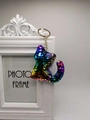 Detailed close-up of a rainbow sequin cat keychain with golden chain on a photo frame - Rainbow