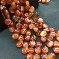 Macro detail of orange agate beads with white stripes spilling from a dark bowl - 10mmx12mm / Red Banded Agate