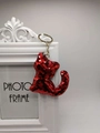 Close-up of cute cat keychain with shiny red sequins and golden metallic ring detail - Red
