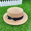 Close-up of woven straw sun hat with black bow ribbon on an artificial grass background - M / With Bow / Light Coffee