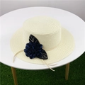 Detalle de un sombrero de paja de ala ancha con una gran flor azul sobre el césped - M (56-58cm) / Blanco Leche