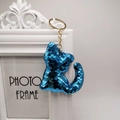 Cute blue sequin cat keychain with gold metal ring on a white vintage photo frame background - Blue