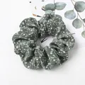 Detailed close-up of dark green floral scrunchie with white leaf pattern on white surface - Grass Green Bellflower