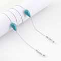 Cadena para gafas plateada con cuentas de turquesa azul sobre fondo blanco - Estilo de Turquesa en Gota de Agua Plateada