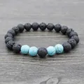 Lava stone yoga beaded bracelet with blue turquoise accents on a wood background - Synthetic Turquoise