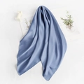 Blue silk scarf with smooth satin finish displayed on white background with decorative props - Haze Blue