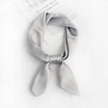 Detail of soft grey square silk scarf tied in a knot on a white background with a book - Light Gray
