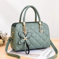 Elegante bolso acolchado verde claro con colgante de mariposa dorada en mesa de madera - verde claro