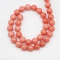 Natürliche pfirsich-orangefarbene Edelsteinperlen für DIY-Schmuck auf weißem Stoff - 4mm Größe / Orangerot
