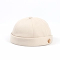 Detalle de gorro docker beige de algodón con un pin metálico de hoja de maple dorada - Ajustable / Blanco Roto