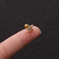 Makro-Detail eines goldenen Stern-Ohrsteckers mit Zirkonia auf einer Fingerspitze - Sternstil Gold (No.9 Gold) / 1.2x6mm (Stabdicke x Länge)
