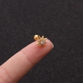 Nahaufnahme von goldenem Stern-Ohrstecker mit weißen Zirkonia, zwischen Fingern gehalten - Achteckiger Stern Gold Stil (No.7 Gold) / 1.2x6mm (Stabdicke x Länge)