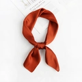 Detail of rust orange satin square scarf featuring silky texture and elegant knot - Caramel color