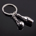 Polished silver metal bowling ball and pin keychain on a black reflective background - Bowling