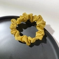 Detail of yellow satin hair scrunchie with pleated texture on a black aesthetic tray - Yellow