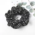 Detail of black floral scrunchie with white leaf patterns and soft textured fabric - Black Bellflower
