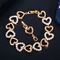 Elegante bracciale a cuore dorato con pietre di zircone bianco su sfondo blu testurizzato - Oro