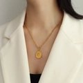 Gold oval pendant necklace with floral engraving on a Figaro chain worn by model - P1023 Gold Color Plum Blossom Tulip