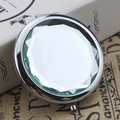 Silver metal folding makeup mirror with pale green faceted gem-cut design on vintage books - Crystal White