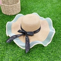 Natural straw sun hat with wavy lace trim and black bow ribbon on green lawn - Khaki