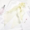 Close-up of light yellow satin ribbon hair scrunchie with soft silk-like texture - Beige