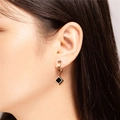 Orecchini a cerchio dorati con ciondolo a rombo nero mostrati su una modella di profilo - Stile Oro Rosa Nero (E157)