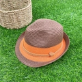 Cappello di paglia marrone con fascia arancione decorativa su un prato verde - caffè