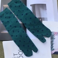 Detailed close-up of green Tabi split-toe socks with blue numbers on top of magazines - Dark Grass Green