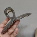Detail of a large translucent grey hair claw clip showing the inner golden spring component - Gray