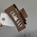 Detail of a large square mocha brown shark clip with a glossy finish and hollow design - Coffee