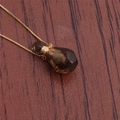 Macro view of flame-shaped brown crystal perfume bottle pendant with gold chain - NSN0230 Smoky Quartz