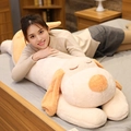 Grand oreiller en peluche chien beige et orange tenu par un mannequin au lit - 60CM / Blanc Cassé