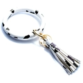 Close-up of stylish cow print silicone wristband keychain with matching tassel and gold hardware - Cow Print