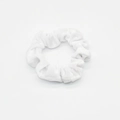 Detail view of a white velvet scrunchie showing soft fabric texture and elastic pleats - White