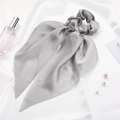 Detail of grey satin bow scrunchie with long ribbons on silk background with pearls - Gray