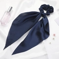 Detailed view of dark blue satin scrunchie with long ribbon bow on white silk fabric - Navy Blue