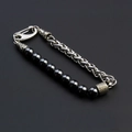 Macro view of men's punk bracelet featuring black beads and a chunky silver metal chain - Hematite