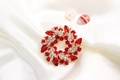 Spilla a ghirlanda con gemme rosse e strass su elegante sfondo in seta bianca - Rosso