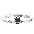 Détail macro de perles en pierre de marbre blanc et d'une breloque couronne noire sertie - Howlite Avec Couronne Gris Anthracite