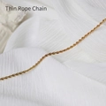 Macro detail of a thin gold rope chain necklace showing intricate spiral texture on silk - Thin Twist Chain / 60 cm / Gold