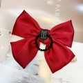 Haargummi mit weinroter Satin-Schleife und Handmade-Etikett auf schickem Hintergrund - Hellweinrotes Haargummi