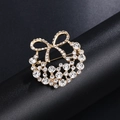 Golden bow wreath brooch with sparkling crystals and pearl accents on black stand - Gold Bowknot Wreath