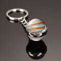 Macro shot of Jupiter pattern glass dome keychain with metal ring on reflective surface - Jupiter